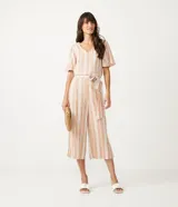 Mono enterizo pantacourt color beige con rayas verticales blancas, escote en V, mangas cortas y cinturón de lazo.