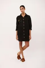 Vestido camisero corto negro de lino italiano con botones frontales, manga larga y bordados de frutas en el pecho.