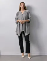 Camisa celeste de tencel, corte amplio, con cuello mao, escote en V y abotonadura frontal. Tiene bolsillos aplicados en el pecho, mangas 3/4 regulables con presilla y ruedo desflecado.