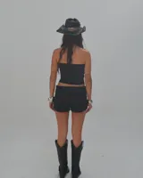 Short negro de tiro alto con cintura ancha adornada con ojales metálicos.