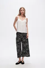 Musculosa blanca de bretel ancho con cuello en V y detalle de ojales metálicos en los tirantes. Corte al cuerpo.