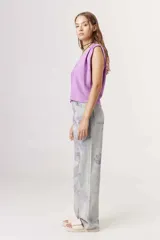 Pantalón de jean celeste con estampado de flores color lila.