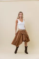 Pollera corta asimétrica de gamuza color marrón, con volados superpuestos y cintura elastizada. Incluye short interno.