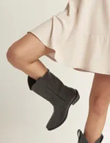 Botas de cuero negro con bordado decorativo en el caño y empeine, taco bajo y punta fina. Diseño de estilo cowboy.