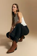 Jean de corte wide leg y tiro alto, color negro con costuras en contraste color ocre. Presenta bolsillos delanteros y traseros con detalle de pespunte, y ruedo ancho con costura decorativa.