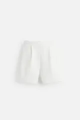 Bermuda relaxed fit color blanco confeccionada en tejido interlock de algodón con elasticidad. Cintura elástica ajustable con cordón interior. Bolsillos laterales y detalle de bolsillo trasero de plastrón.