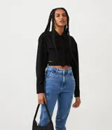Camisa cropped negra de viscosa con cuello camisero, manga larga con puños abotonados, bolsillos de parche en el pecho, cierre frontal con botones ocultos, recortes laterales y elástico en la espalda.