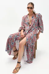 Vestido midi de lino color ladrillo con estampado floral celeste, corte recto, cuello mao, mangas abullonadas 3/4 con puños elásticos, cierre frontal con botones y falda con volantes.