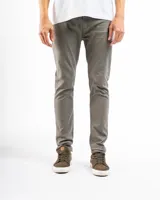 Pantalón de gabardina color beige, de corte recto, con bolsillos laterales y traseros. Se ajusta a la cintura con cinturón de cuero marrón.