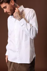 Camisa blanca de manga larga con cuello clásico y cierre frontal con botones.