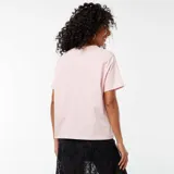 Camiseta rosa de corte amplio con estampado de texto en rojo que dice "New York, Sleepless Nights and City Lights" y dos estrellas.
