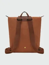 Mochila plegable Longchamp modelo Le Pliage Original, color beige claro, con solapa y asas de cuero marrón.