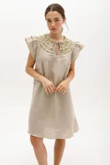 Vestido corto celeste de lino, corte suelto, con cuello redondo con volados y lazo, mangas cortas con volados.