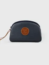 Neceser azul marino de cuero con cierre superior y parche circular de cuero marrón con logo en el frente.