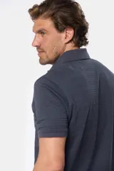 Chomba azul con textura de líneas horizontales en relieve, cuello clásico y tapeta con dos botones.