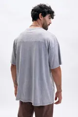 Remera de manga corta, corte oversize, color gris con efecto lavado (acid wash). Presenta un estampado minimalista en el pecho con texto que incluye "VILLA CLUB / SEASON 01".