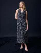 Vestido largo Donna Ricco de gasa color negro con estampado de lunares blancos, escote en V cruzado, sin mangas, cintura con lazo de ajuste y forro interno.