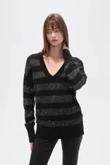 Sweater negro con cuello en V, diseño holgado y mangas largas. Presenta rayas horizontales de lentejuelas plateadas.