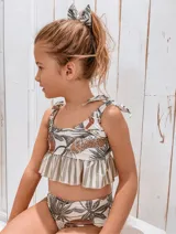 Conjunto de bikini para niña con estampado de hojas y leopardo. El top tiene volados y tirantes con lazos.