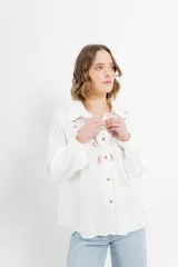 Camisa blanca de voile con bordados calados en el frente, manga larga con puños abotonados y cuello camisero clásico.