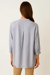 Camisa color crema de viscosa, corte holgado, con cuello mao y cierre frontal con botones.