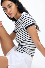 Remera entallada de punto suave a rayas horizontales blancas y azul marino, con ribete fino en cuello y mangas.
