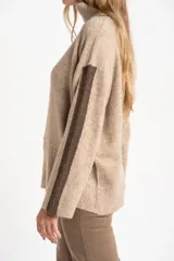 Sweater negro de tejido grueso con cuello alto acanalado. Presenta una franja decorativa en las mangas y el cuello en hilo marrón con brillo (lurex).