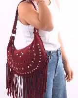 Bolso de hombro tipo boho, color bordó, confeccionado en gamuza con tachas plateadas y flecos largos. Tiene correa doble para usar al hombro o cruzado, forro interior y bolsillo interno.