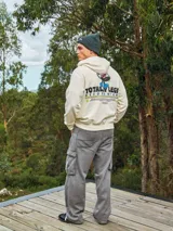 Hoodie color crema con capucha y manga larga, de corte holgado y estampado frontal con un personaje de caricatura y la frase "Totally Legit".