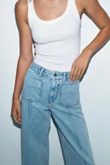 Jeans de tiro alto con corte wide leg cropped, confeccionados en denim de lavado claro. Presentan costuras marcadas en el frente, bolsillos de plastrón delanteros y cierre frontal con cremallera y botón.