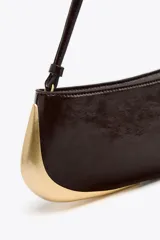 Bolso de hombro marrón oscuro con detalle metálico dorado en un lateral. Tiene un bolsillo interior con cremallera, asa de hombro y cierre con cremallera.