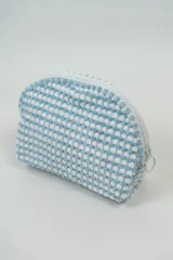 Neceser pequeño con textura de puntos en relieve color rosa y blanco, con cierre superior de cremallera rosa.