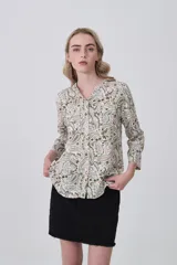 Camisa de manga larga con cuello mao y estampado paisley en tonos blanco, verde oliva y rosado. Presenta un calce holgado y bolsillos frontales.