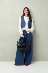 Pantalón de jean negro de calce ultra wide leg, tiro alto y silueta amplia desde la cadera hasta el bajo. Diseño clásico de cinco bolsillos y cierre con botón metálico y cremallera.