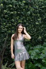 Vestido corto negro con estampado de hojas doradas, escote en V, breteles finos cruzados en la espalda, cut-outs laterales bajo el busto y volado en el ruedo.
