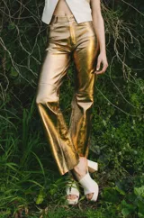 Pantalón de cuero dorado, de corte recto y tiro medio.