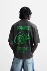 Camiseta gris oscuro con efecto lavado, cuello redondo, manga corta y estampado de textos combinados en verde neón en el delantero y la espalda.