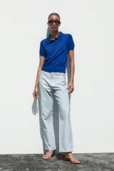 Top azul eléctrico de punto, con cuello polo, manga corta y cierre frontal con botones negros.