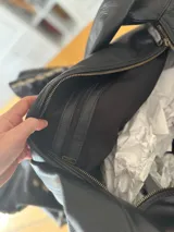 Bolso de hombro grande de cuero negro, con correa ancha y bolsillo interno con cierre.