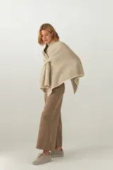 Ruana de tejido de punto industrial color beige, con terminación en contraste de color y doble ojal para mantener el cruce. Confeccionada 100% en lana fina sin teñir, diseñada exclusivamente por Don Baez.