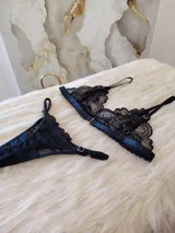 Conjunto de lencería negro de encaje, compuesto por un bralette con breteles regulables y una tanga regulable con corte cola less y entrepierna de algodón.