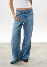 Pantalón de jean celeste de corte wide leg, con diseño de paneles geométricos en las piernas.