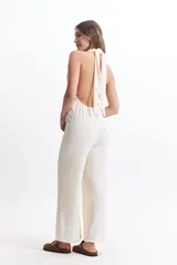 Mono largo color crudo, con escote halter, espalda descubierta y corte palazzo.