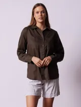 Camisa blanca de lyocell marca Cyrus, con cuello con solapa, abertura central con botones, mangas largas regulables con presilla y botón, y bolsillos delanteros aplicados.