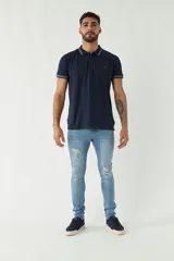 Chomba azul marino de manga corta con cuello polo y detalles de líneas grises en cuello y mangas. Tiene logo bordado en el pecho. Corte regular.