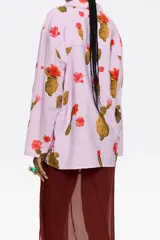 Camisa de viscosa color lila con estampado de cactus y flores rojas, corte recto, cuello con solapas, manga larga recta, cierre frontal con botones y bolsillos de plastrón.