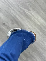 Jean de corte wide leg en denim, con detalles deshilachados en el bajo.