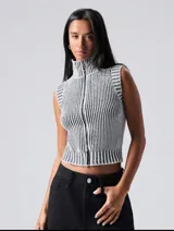 Chaleco tejido de punto con cuello alto y cierre frontal con cremallera, con diseño a rayas verticales en blanco y negro.