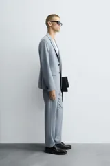 Blazer celeste de corte slim fit, con solapas de muesca, manga larga con botones en los puños, bolsillo de vivo en el pecho, bolsillos de solapa en la cadera, bolsillo interior, aberturas en la espalda y cierre frontal con botones.