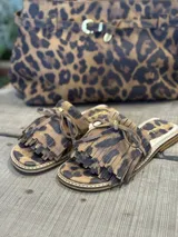 Sandalias bajas con estampado animal print, detalle de flecos y lazo en la parte superior.